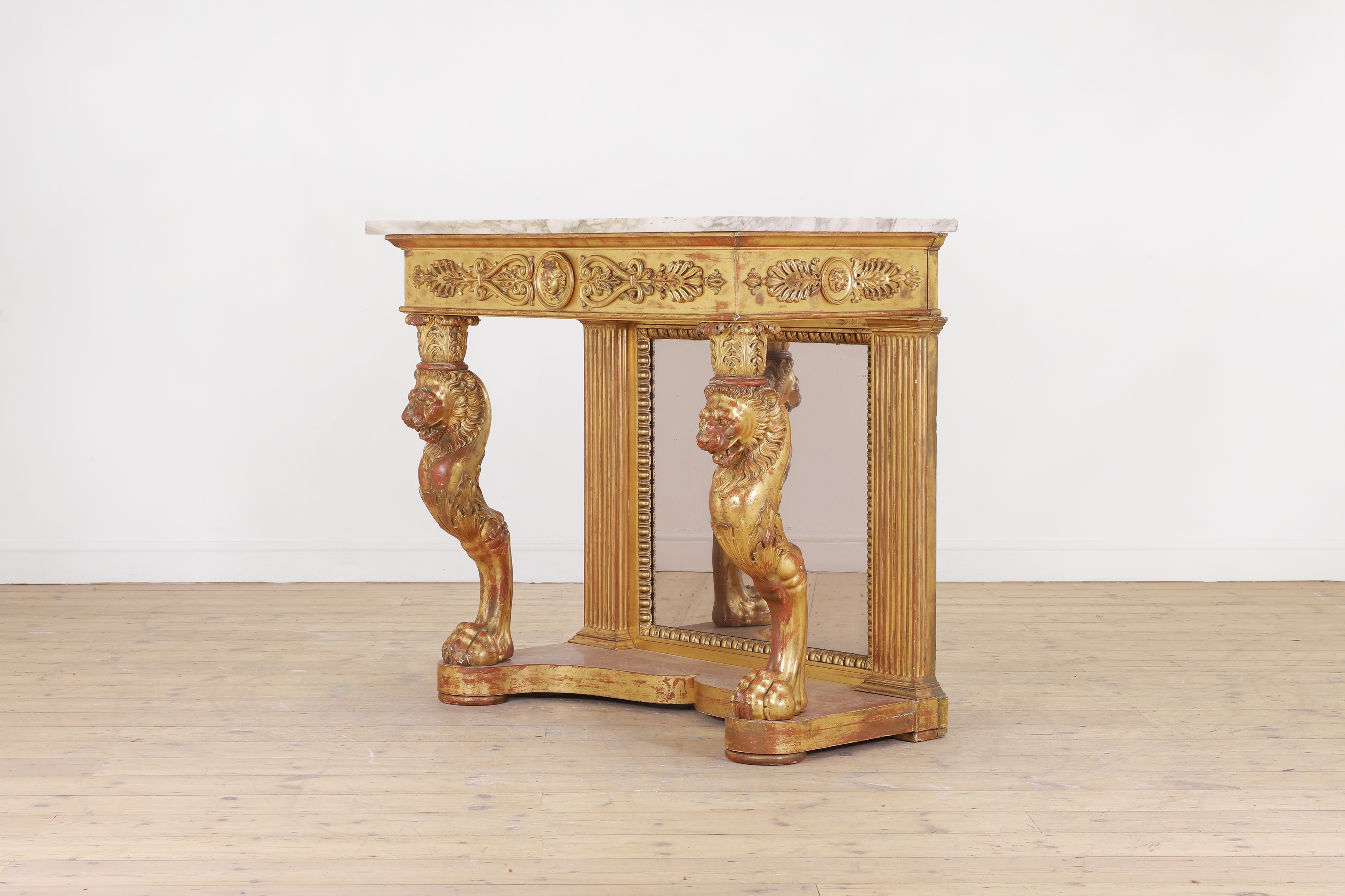 A giltwood console table, early 19th century, with a veined white marble top, above monopodia supports and a mirrored back, on a shaped plinth base, 106cm wide 50cm deep 80cm high (£3,000 - 5,000)